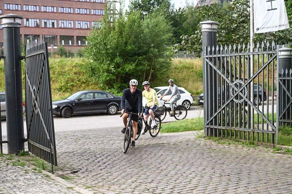 Mehre Personen fahren auf Fahrrädern durch ein Tor auf die Einfahrt